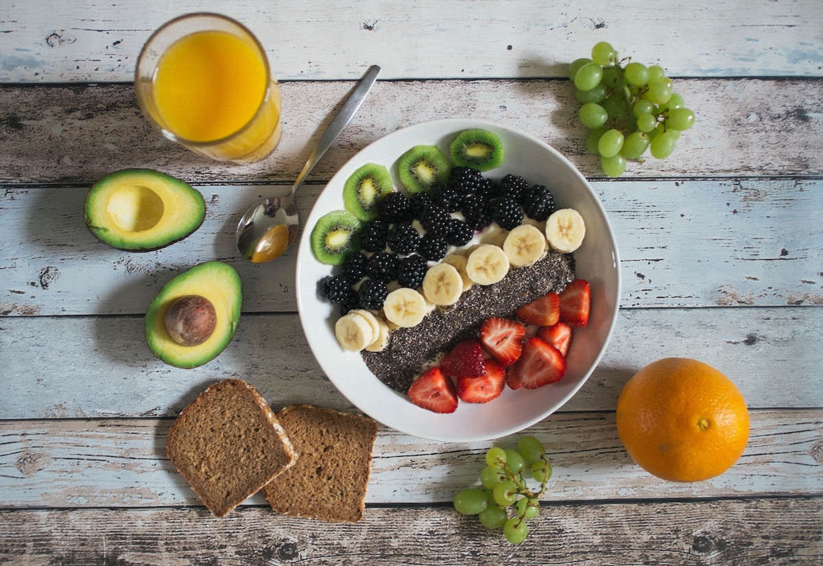 bowl of fruit and chia seeds with toast, fruit, and avocado on table 