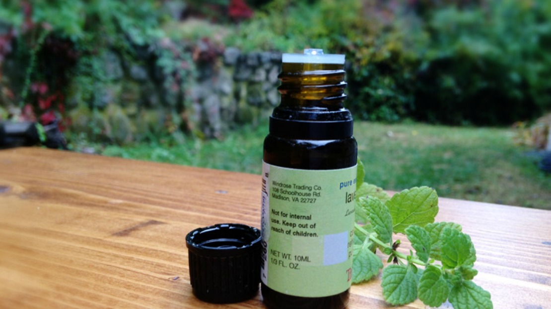 essential oil bottle with cap and mint stem lying next to it