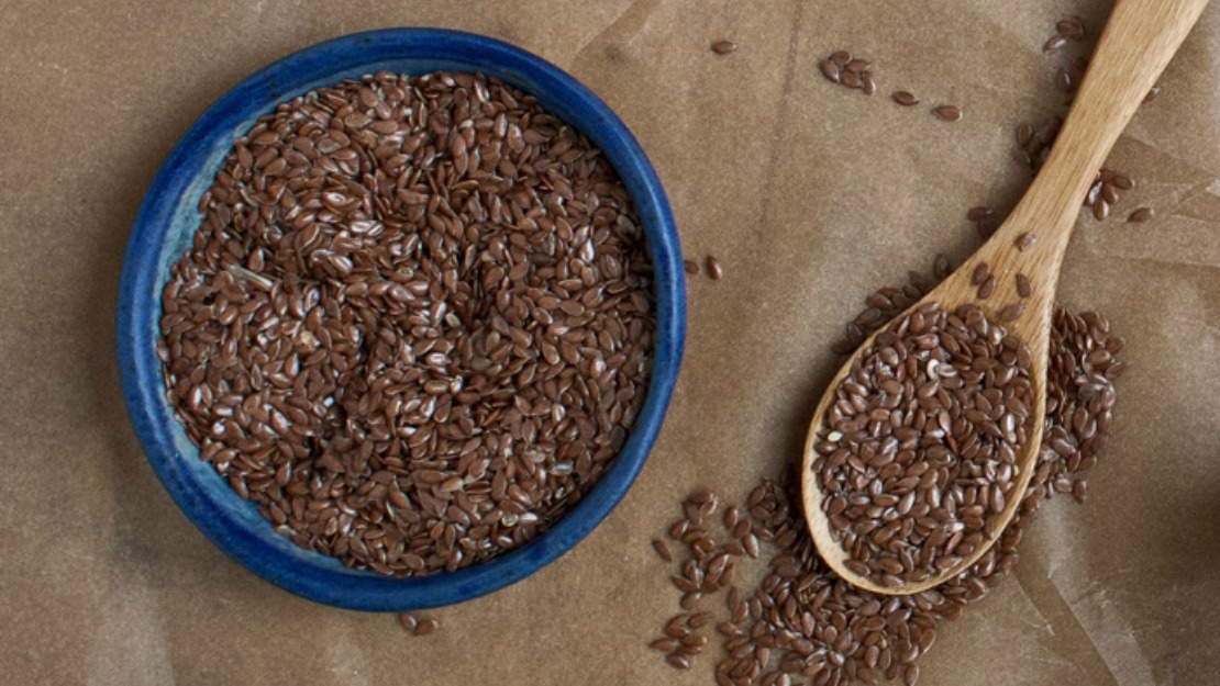 flax seeds in a blue ceramic bowl and on a wooden spoon