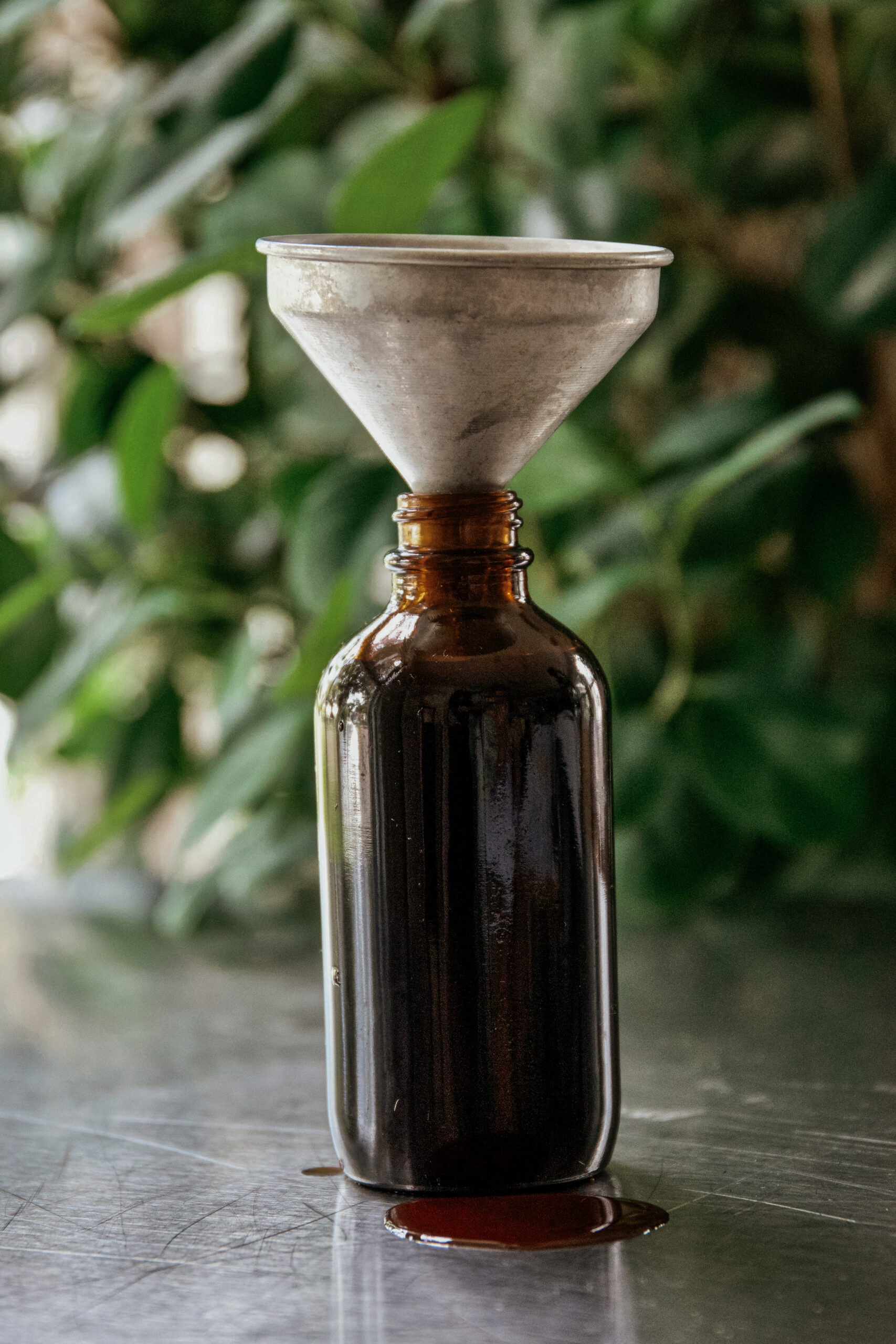 dark amber bottle with a funnel inside and elderberry syrup spilled out