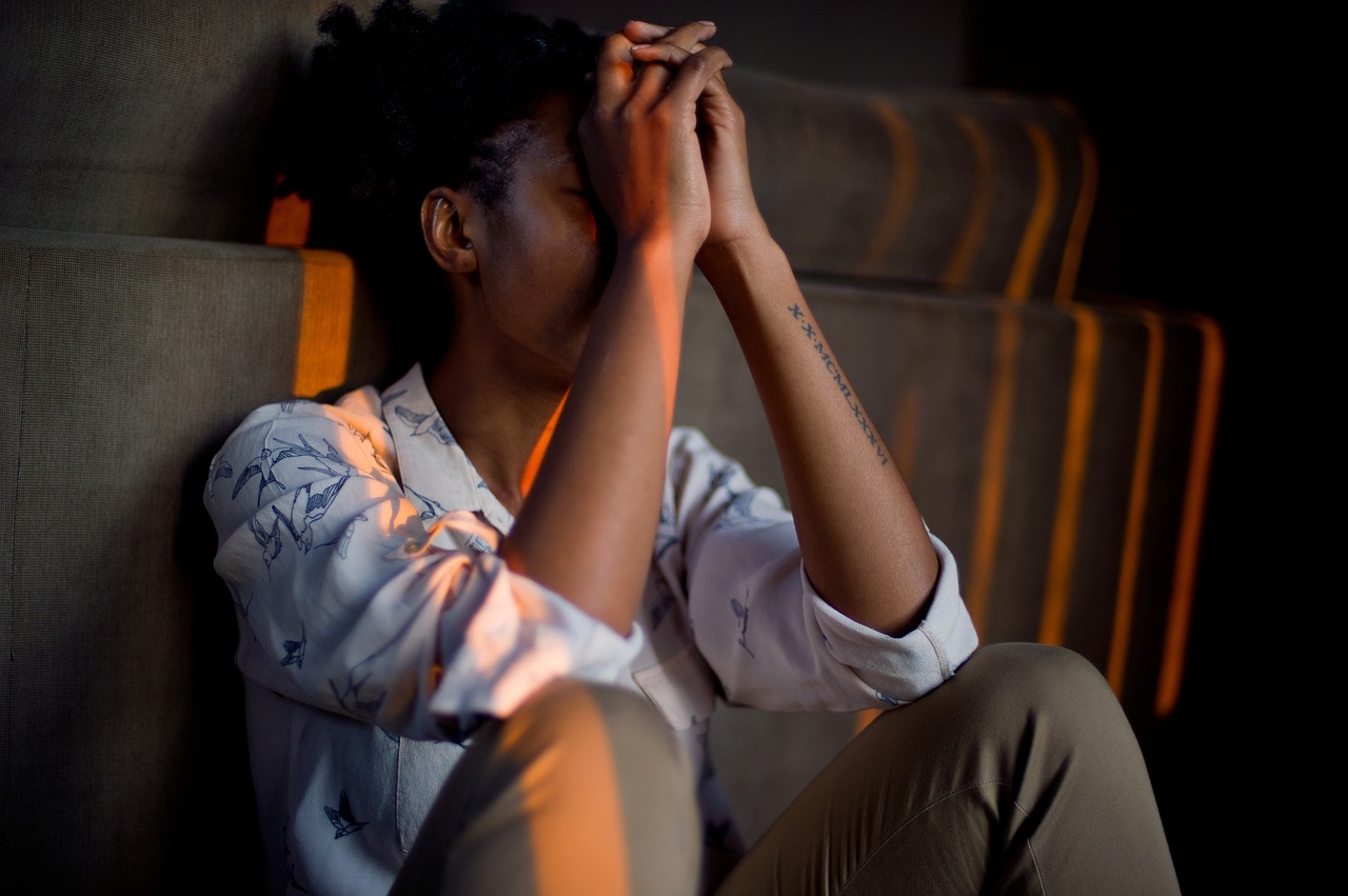 woman sitting with her elbows on knees and hands covering her face looking under stress