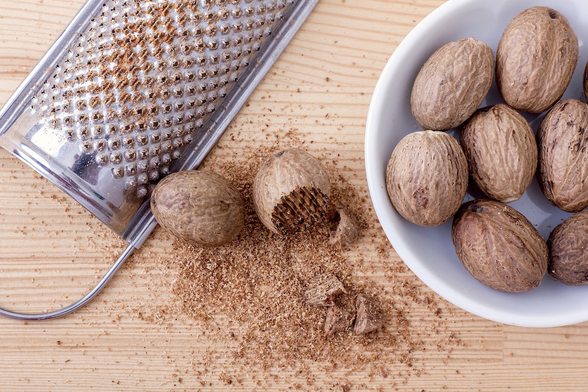 nutmeg in a bowl with grated nutmeg beside it