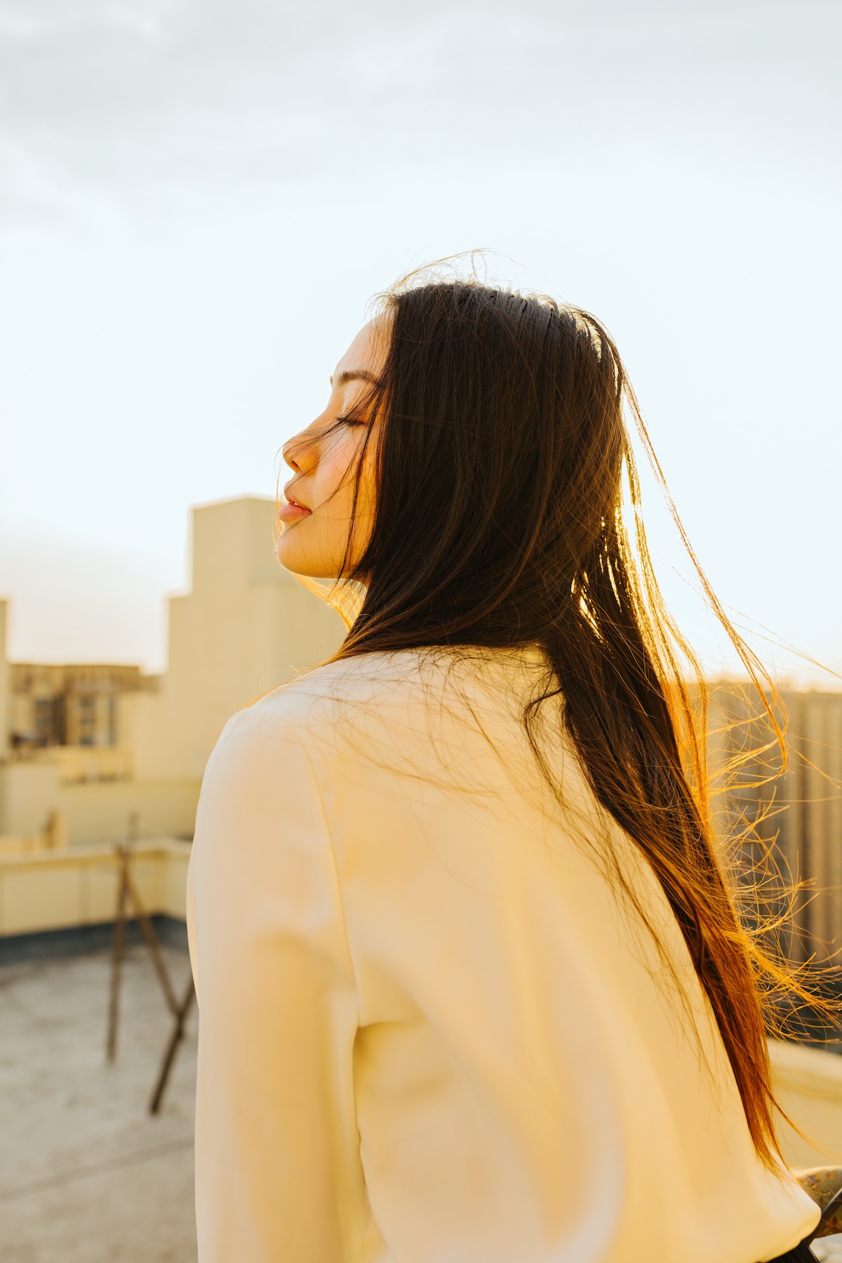 woman closing eyes while turning face to the sun
