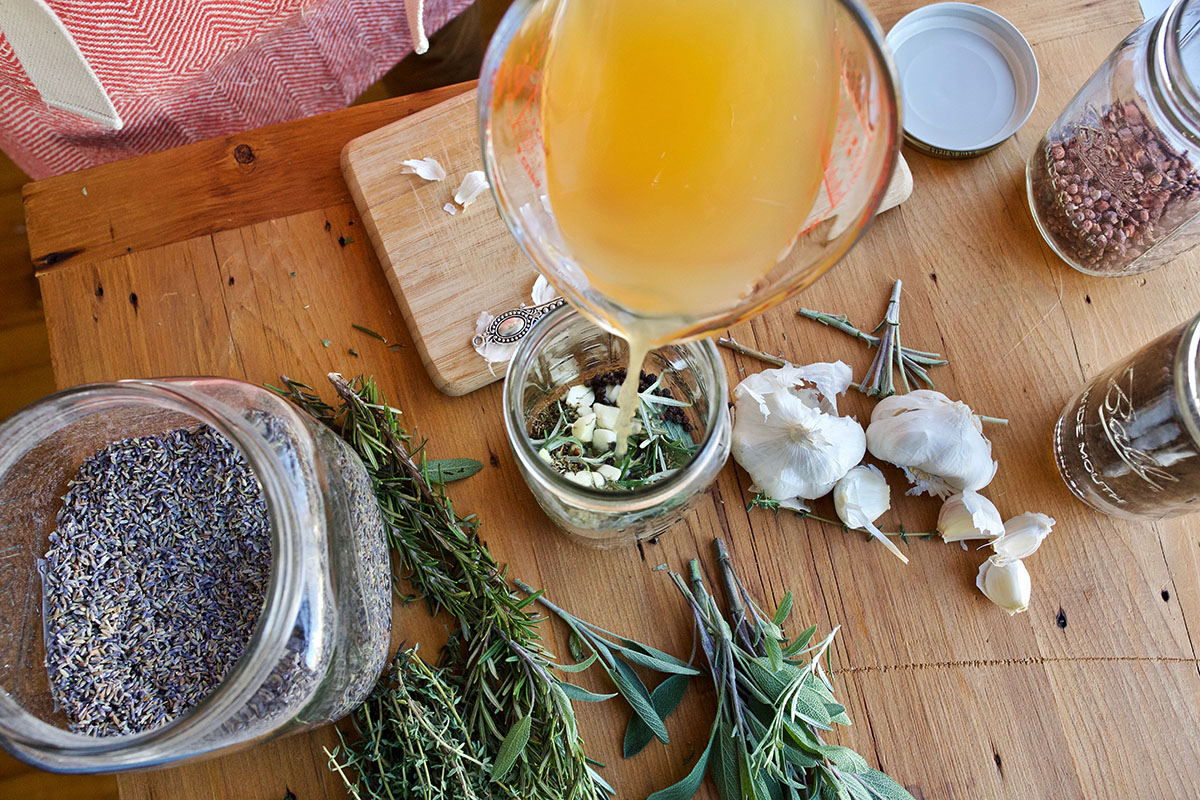 pouring vinegar into a jar of herbs