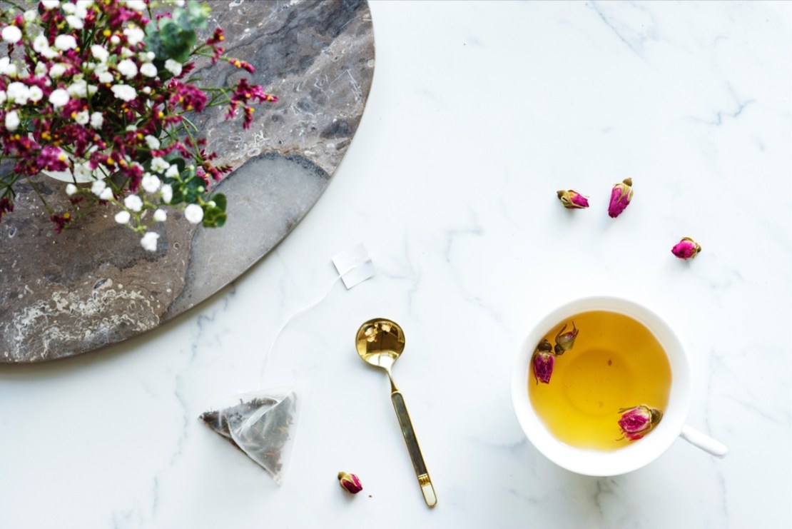 cup of tea, flowers, and spoon on table