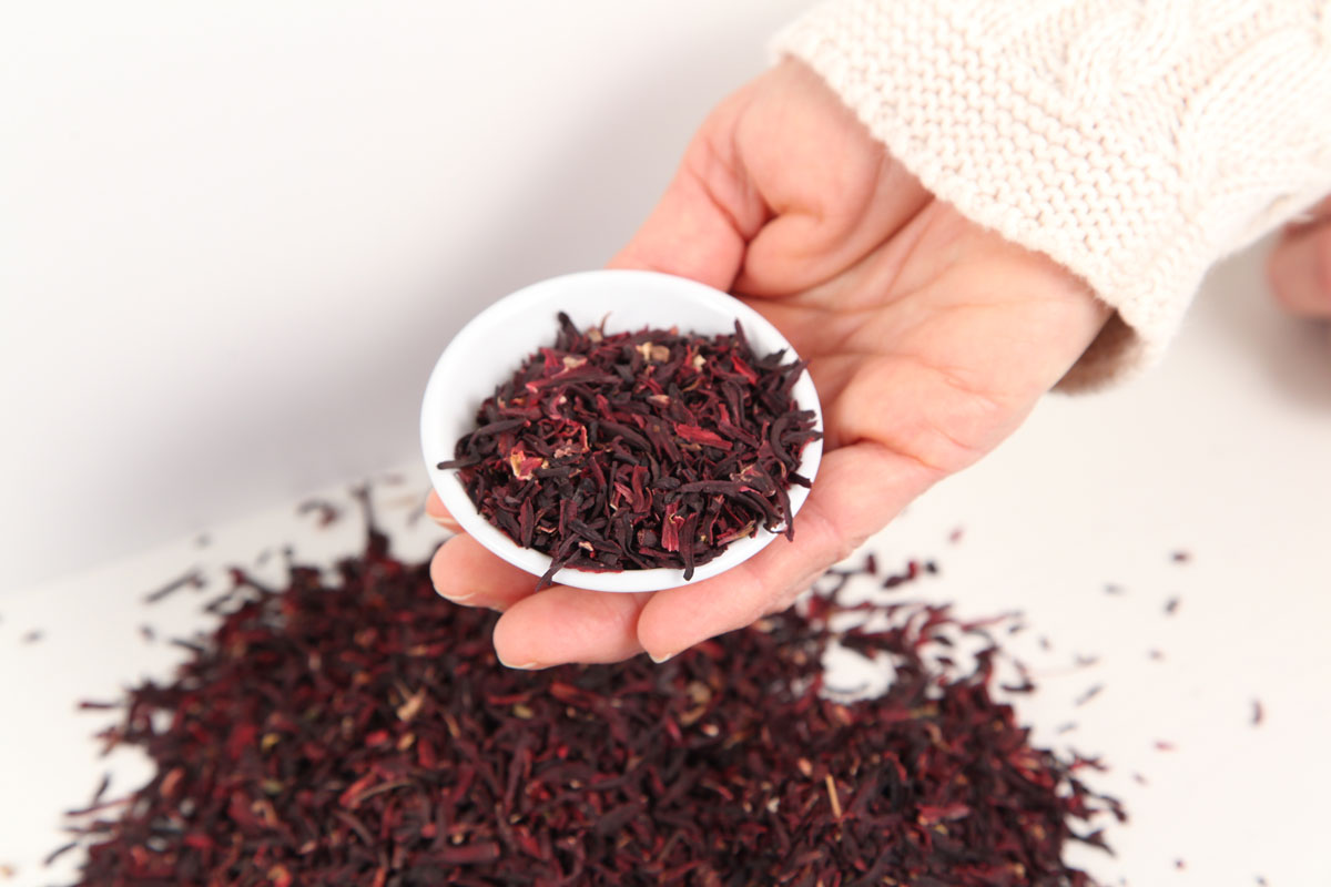 dried hibiscus in a white bowl and scattered on the counter