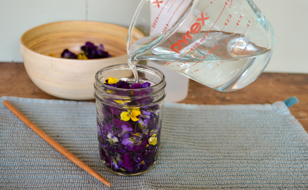 glycerin pouring from measuring cup into a jar of flwoers