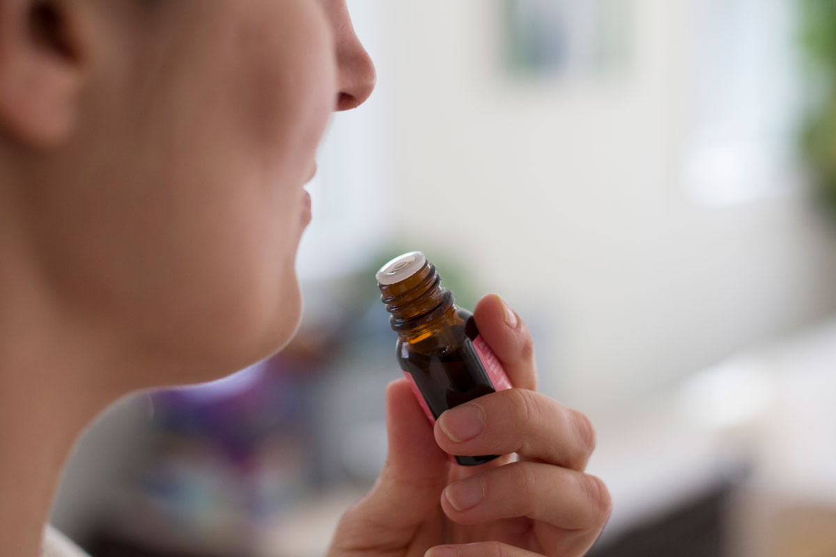 woman inhaling the scent from an essential oil bottle