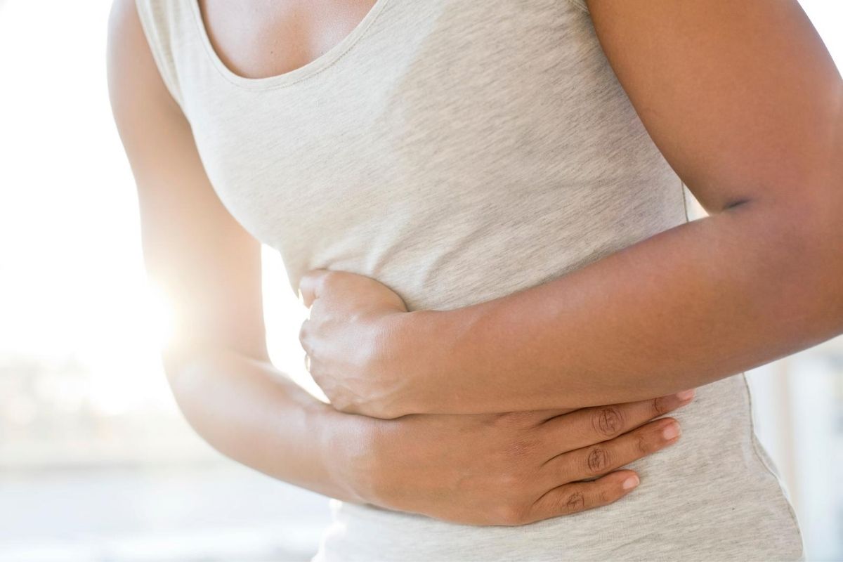 A woman holding her stomach to signify a stomach ache. 