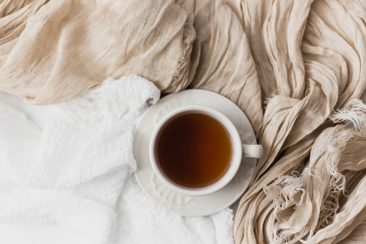 A cup of tea sitting on top of neutral-colored linens