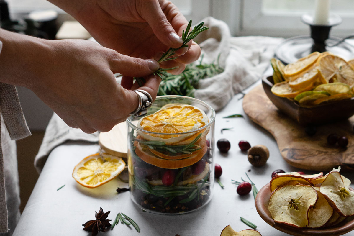 layering oranges and other herbs in a glass container