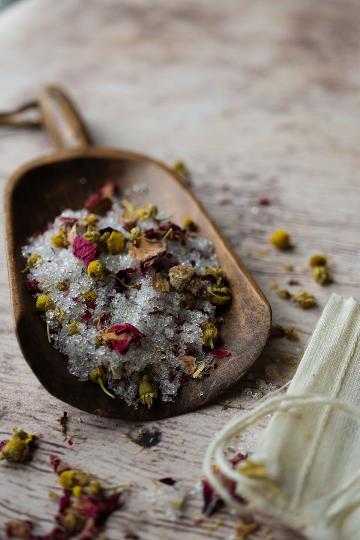 Herbal bath salts on a wooden scoop