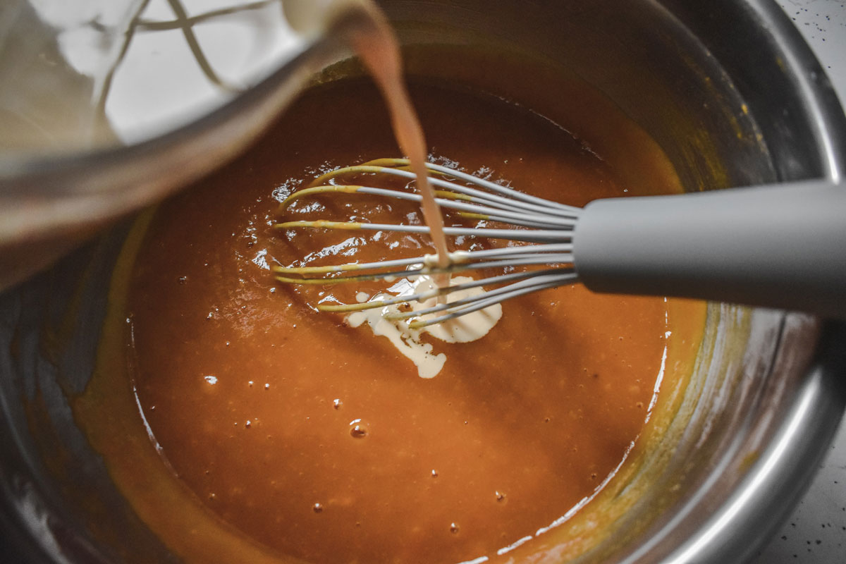 Pumpkin pie batter in a bowl being stirred with a metal whisk