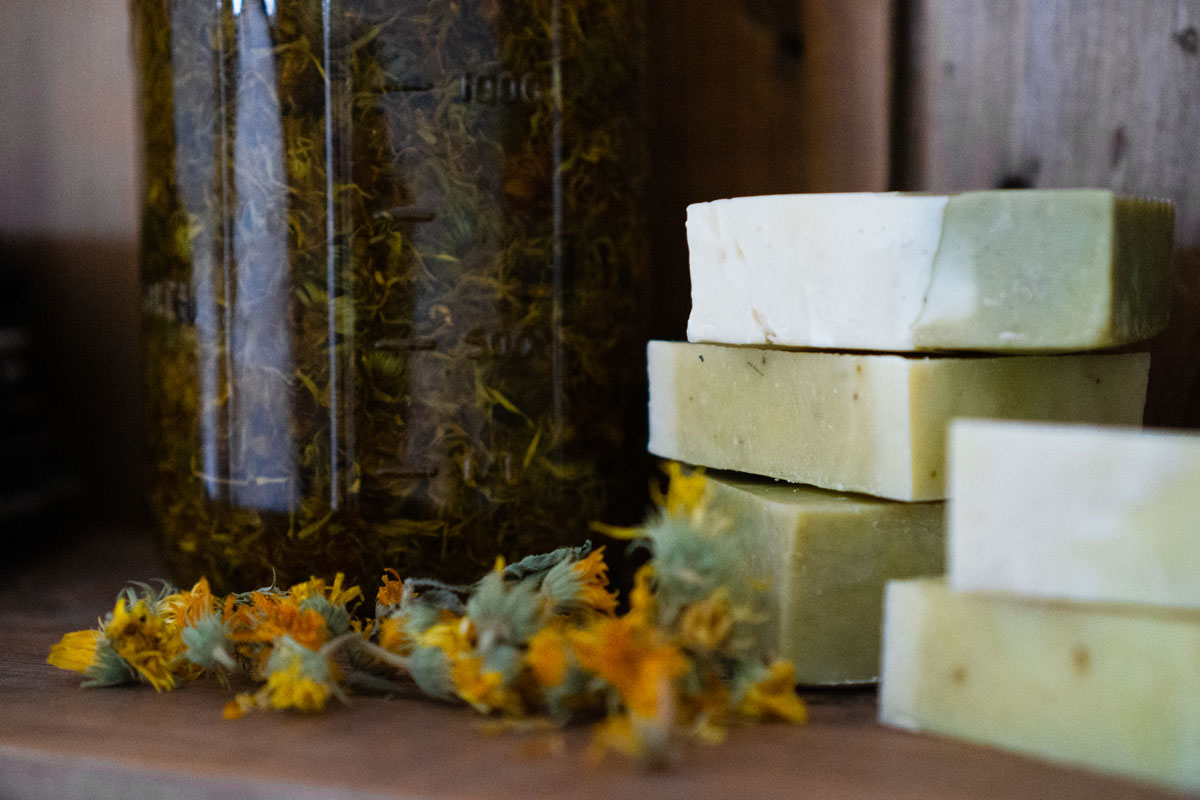 Homemade soap, calendula petals, and calendula herbal oil on a wooden surface