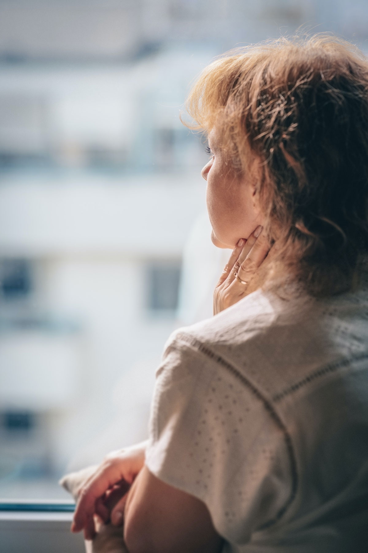 A woman looking sadly out the window with her back to the camera