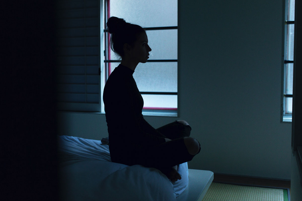 Woman with insomnia sitting on her bed in a dark room