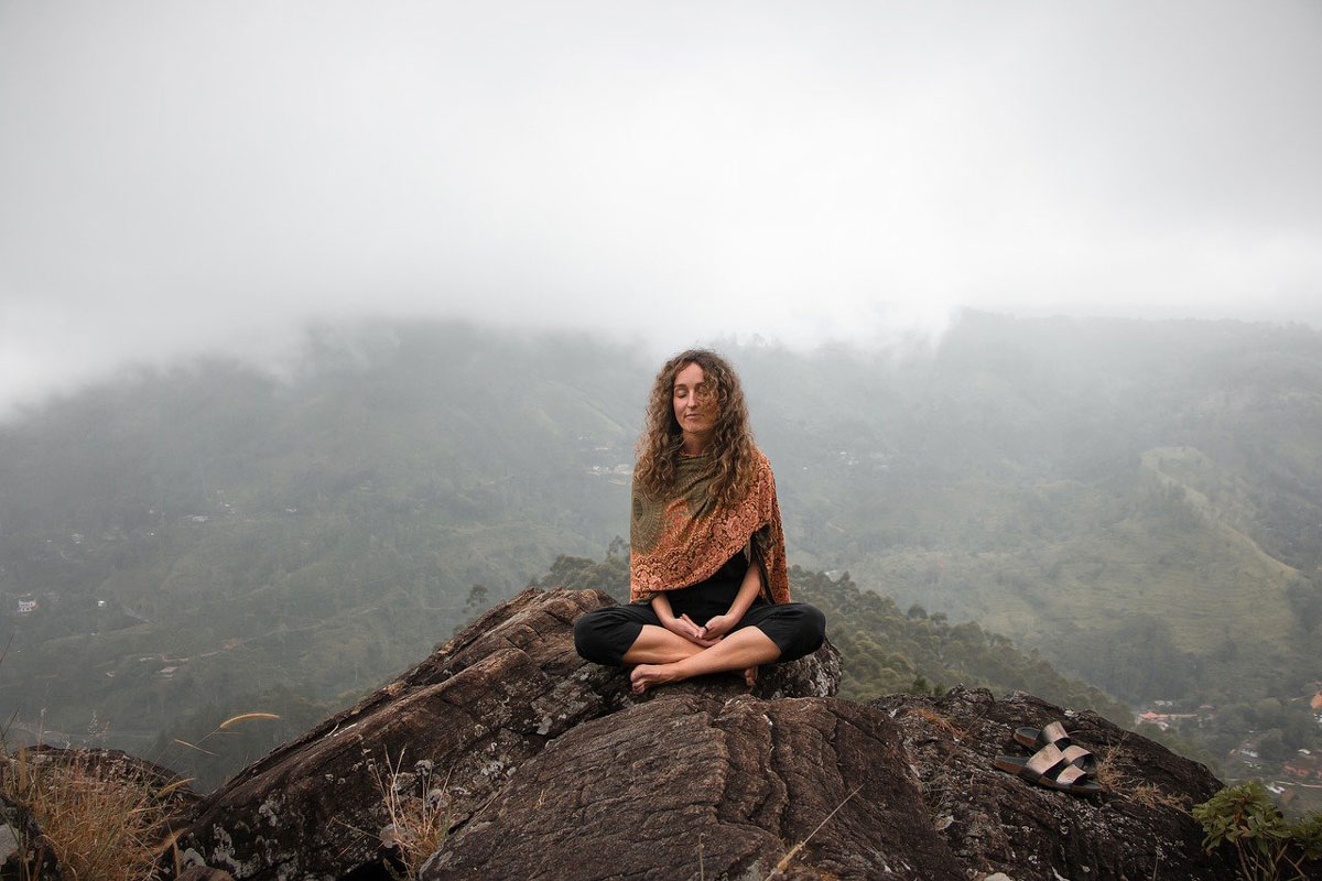 A woman sitting on a mountaintop meditation peacefully