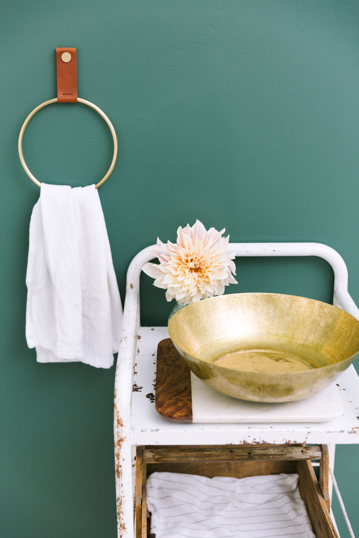 A hanging towel, golden bowl, and white stand ready for a skincare ritual. 