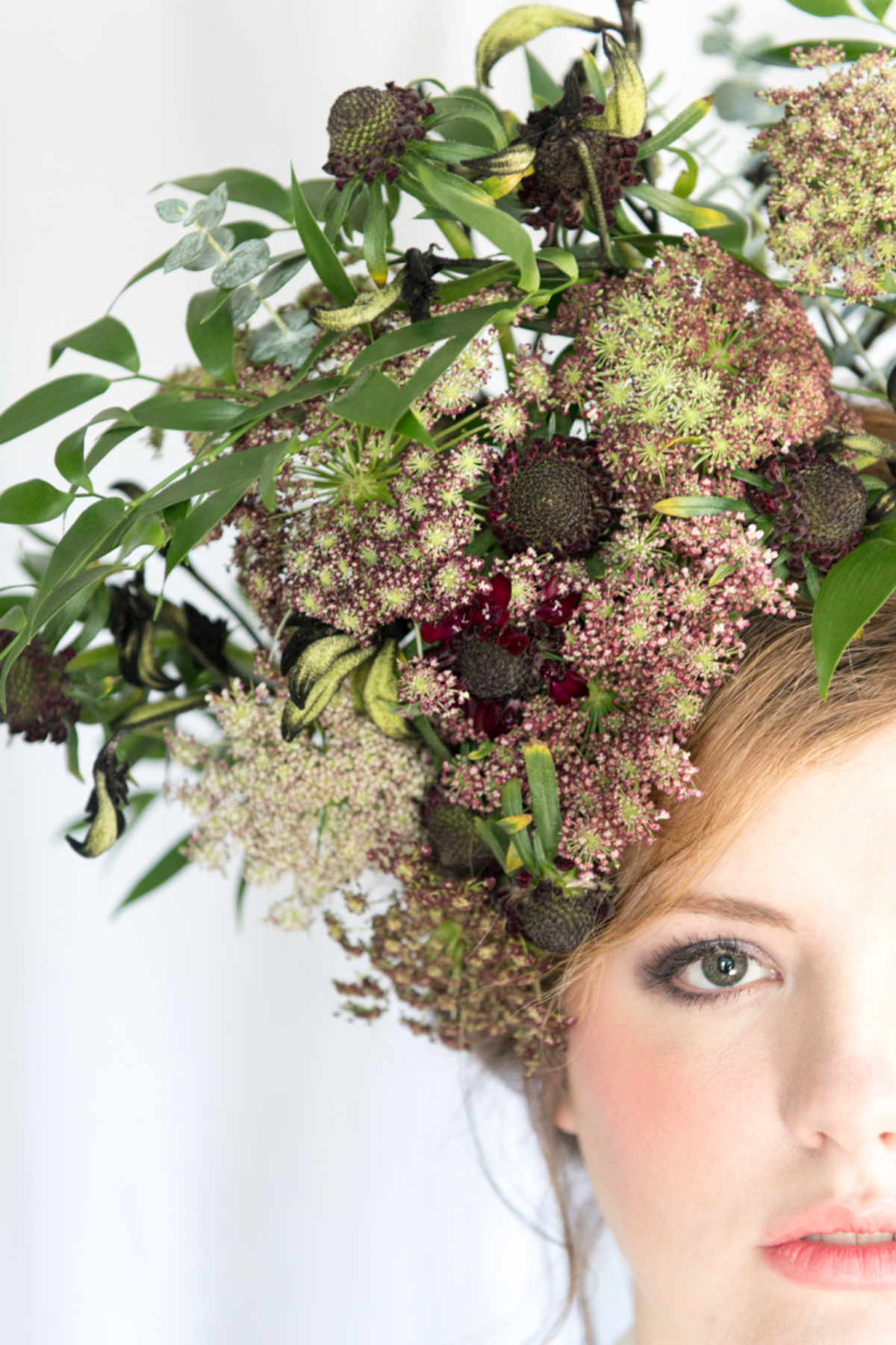 half of a lady's face looking at the camera with flowers in her hair