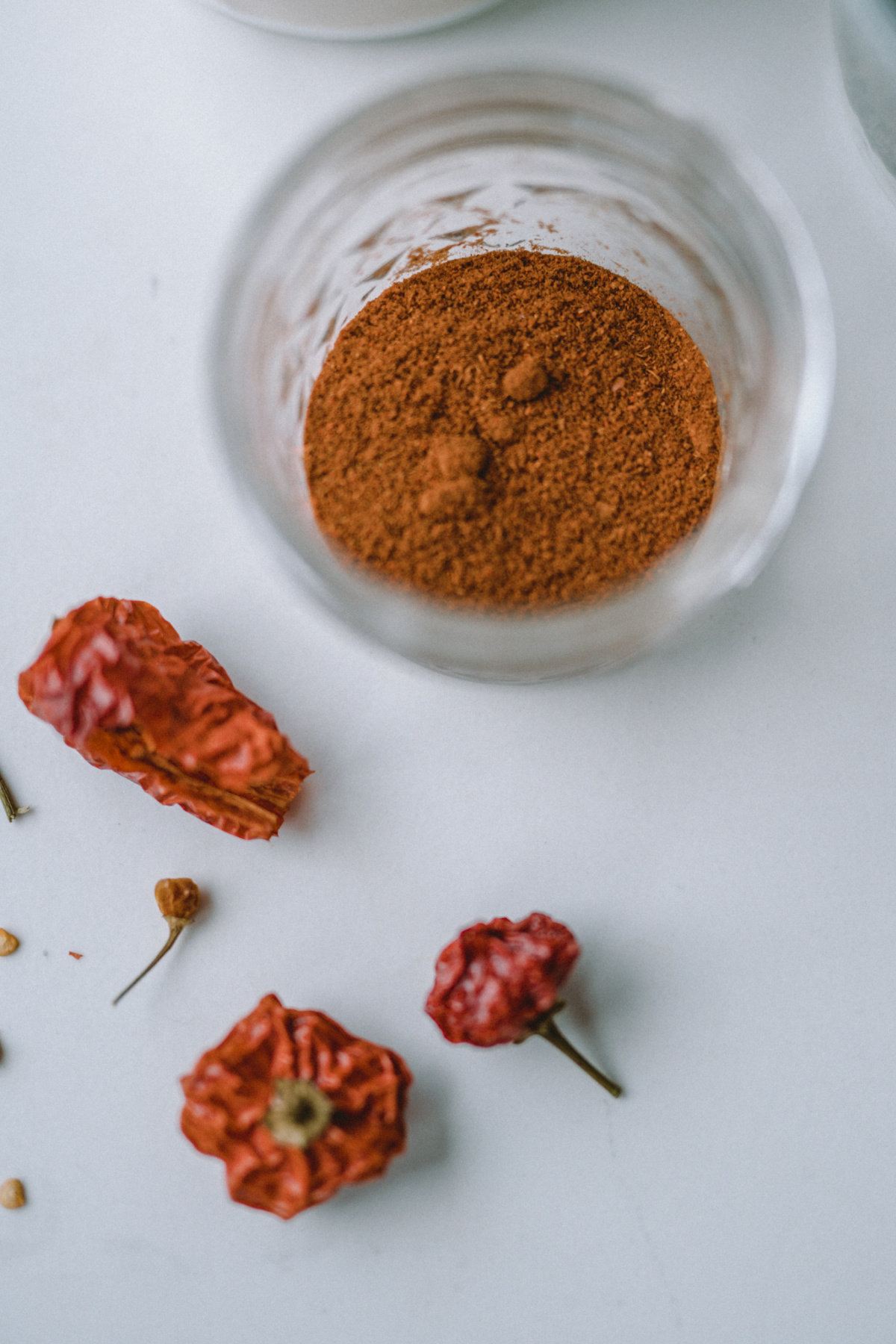 powdered cayenne in a glass bowl with dried cayenne on the table next to it