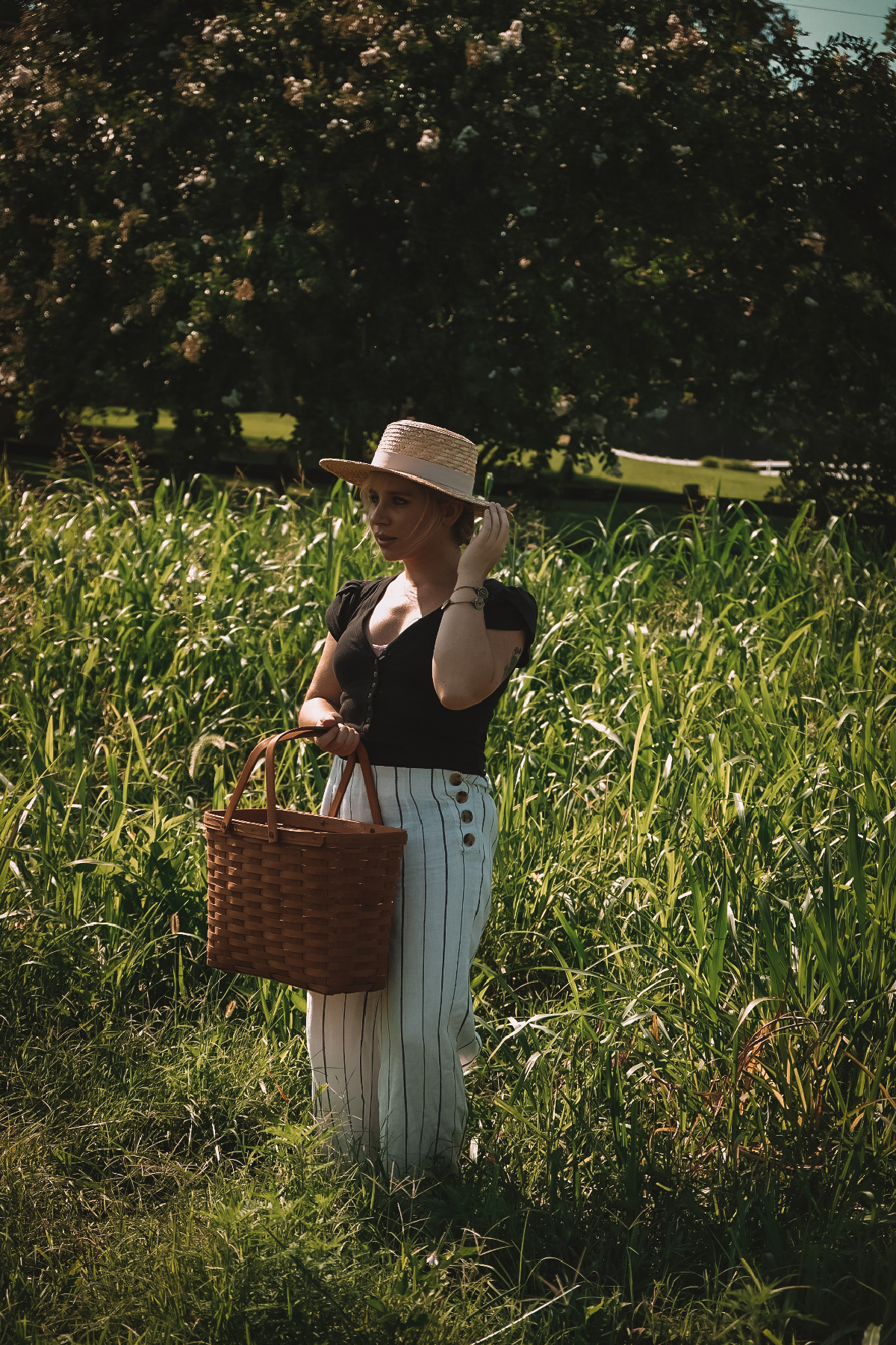 herbalist Caitlin Frazier in a field holding a basket