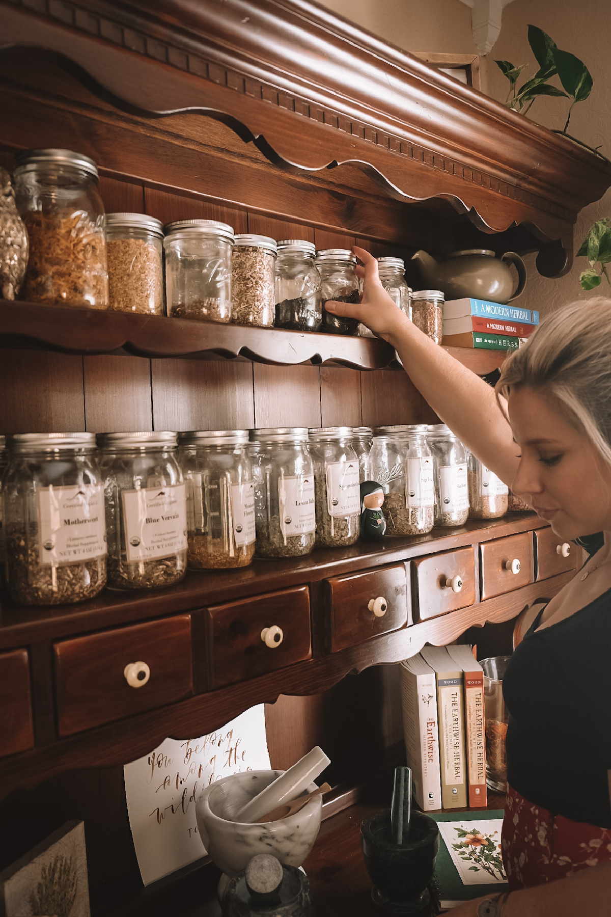 Herbalist Caitlin Frazier reaching for a jar of herbs