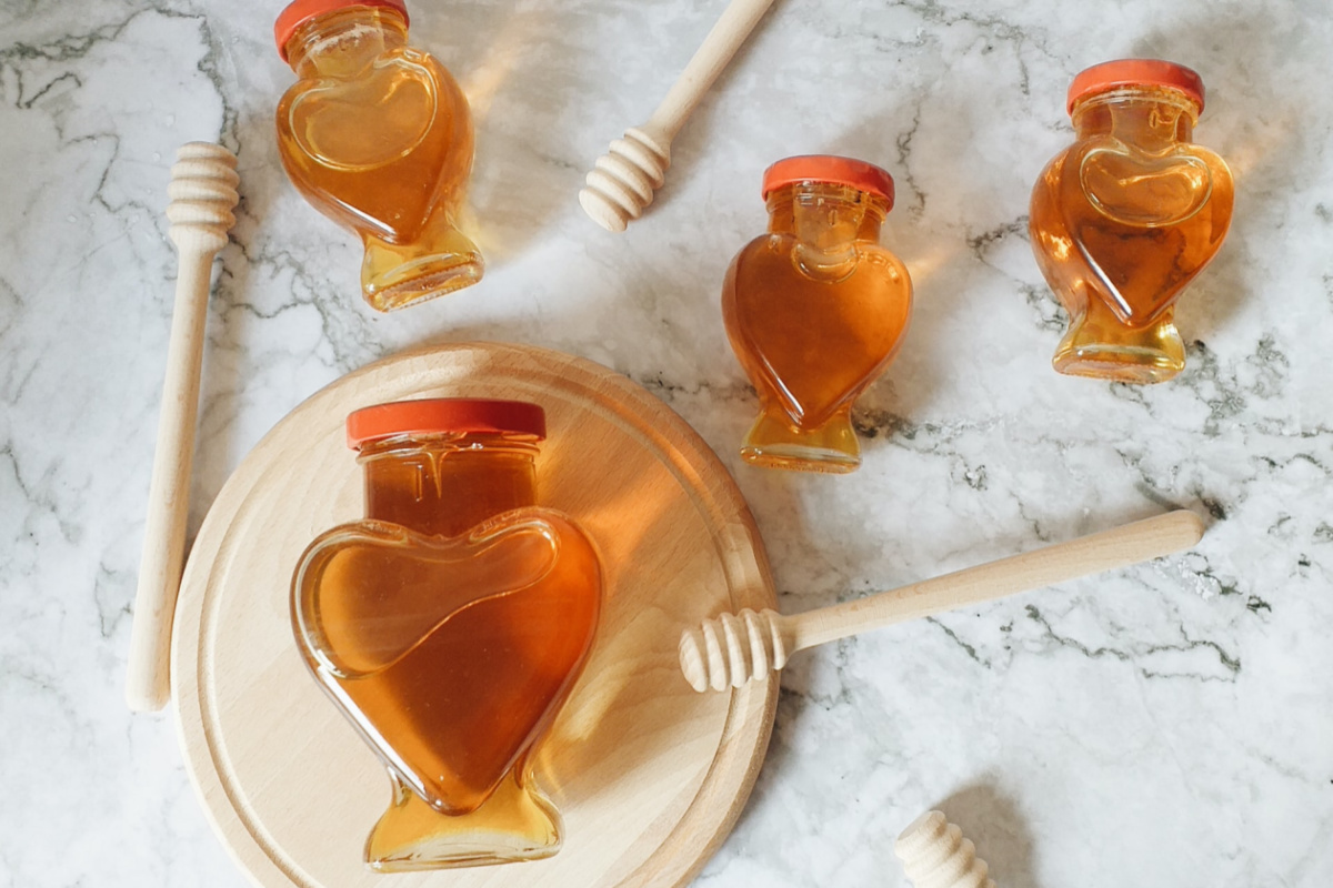 jars of honey with wooden honey dipper sticks