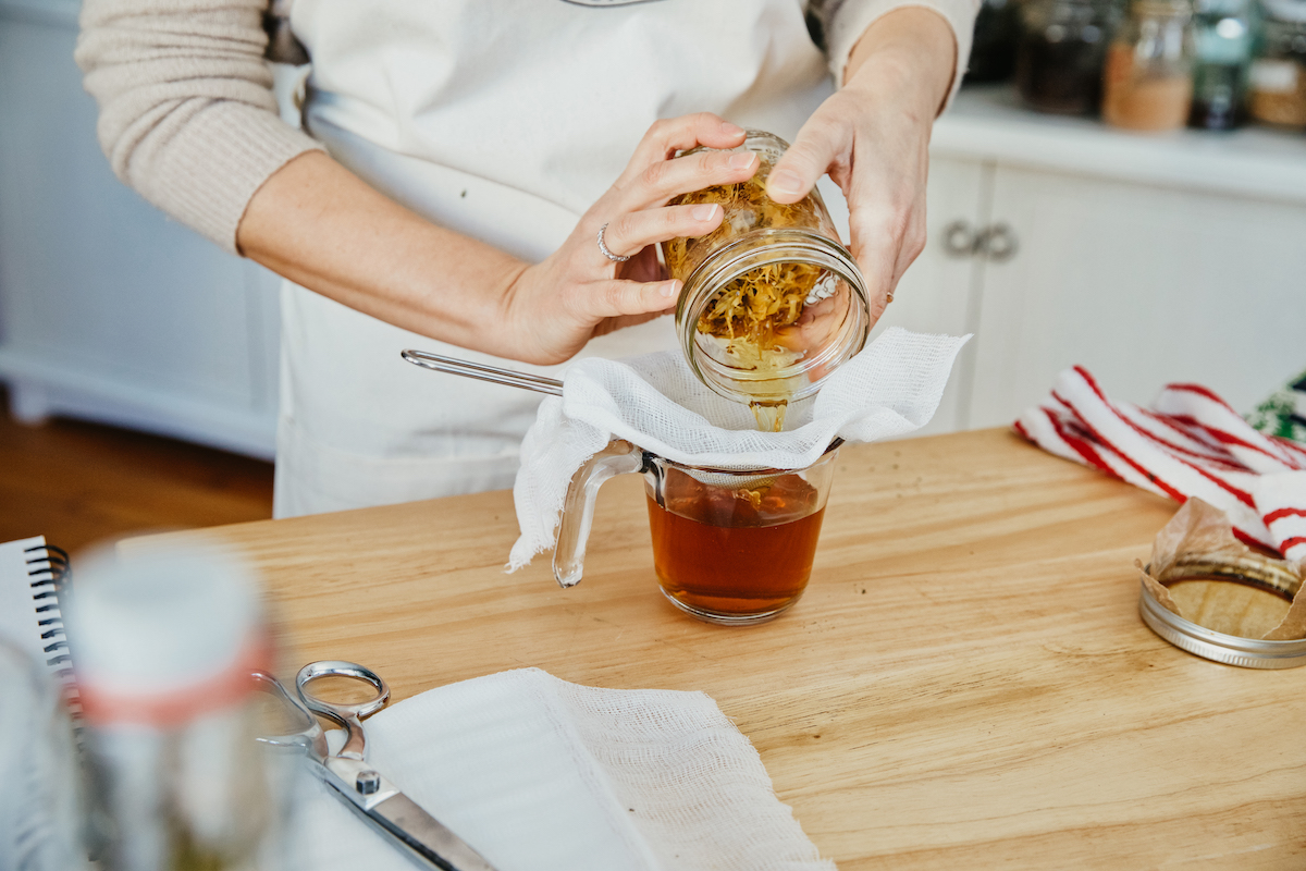 woman straining an herbal tincture