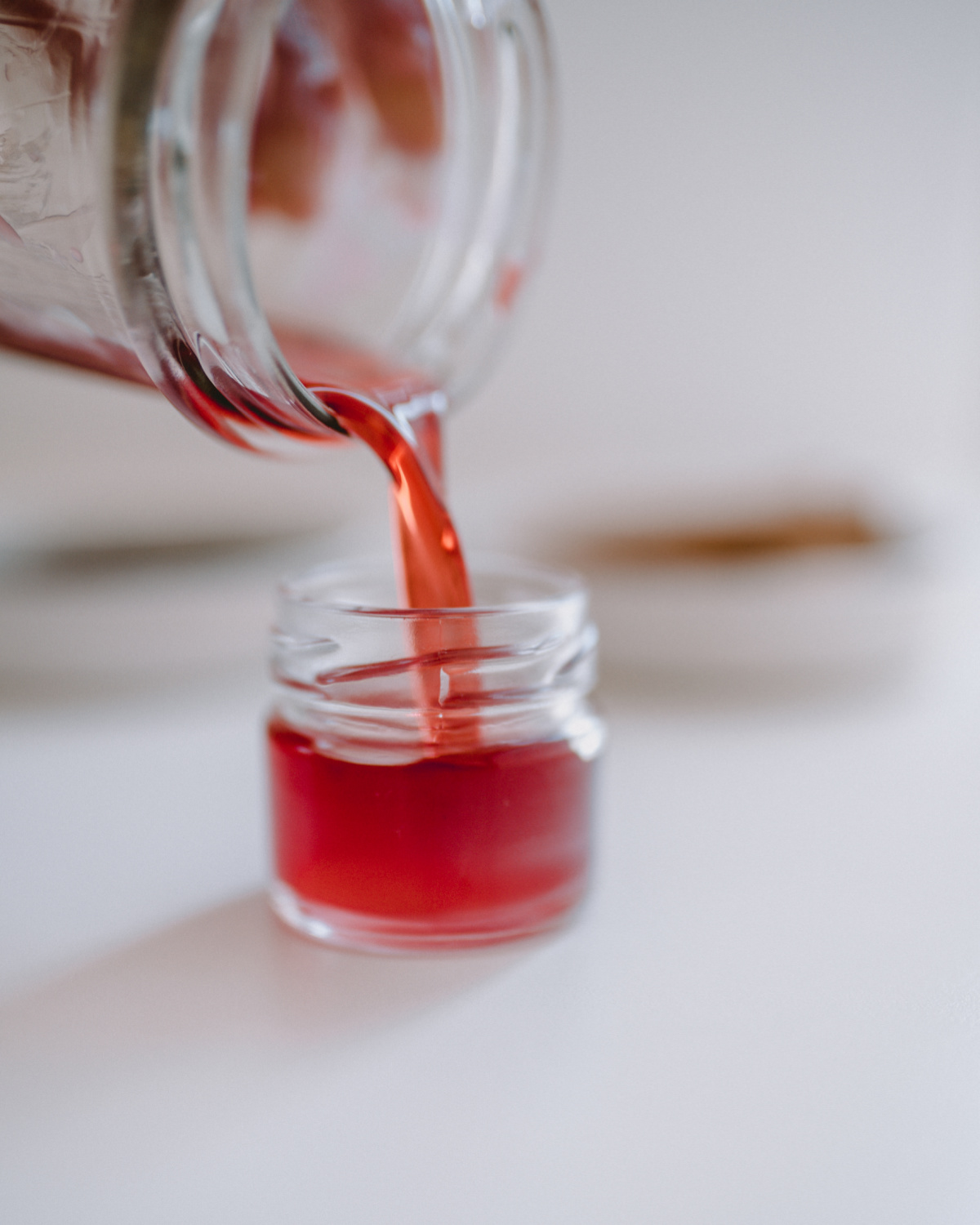 pouring lip balm into a small glass jar