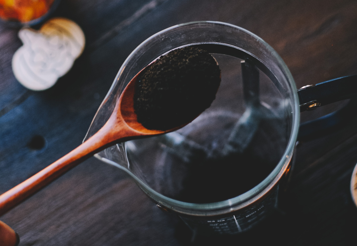 pouring coffee grounds into measuring cup