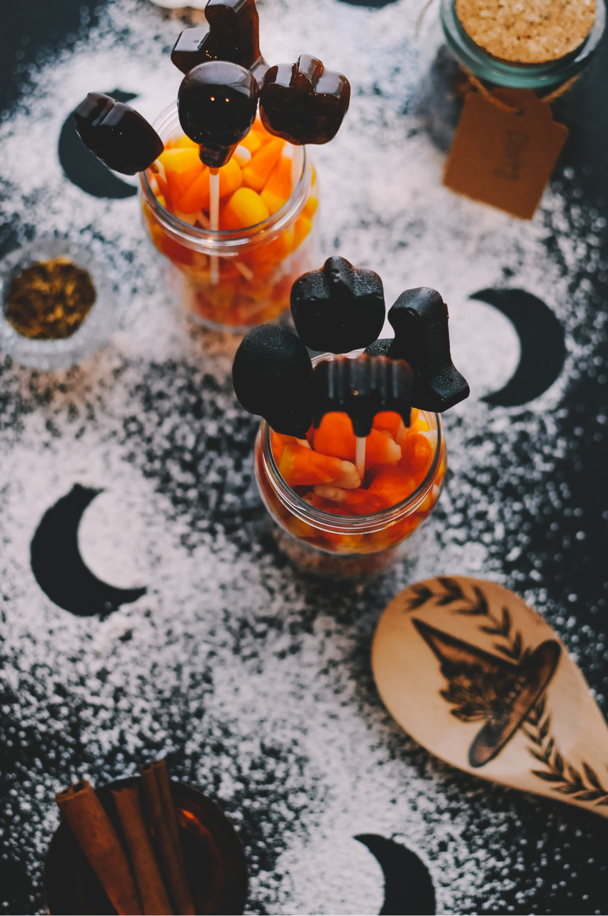 jars of candy corn with herbal lollipops and sugar sprinkled on the table