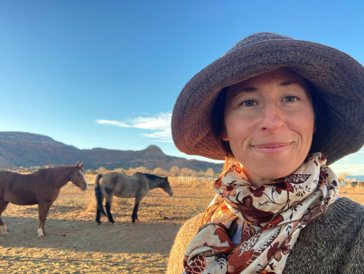 Liz Witter wearing a hat with horses and mountains in the background