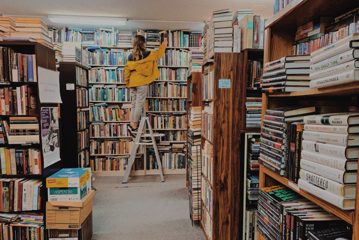 woman on a ladder looking at books