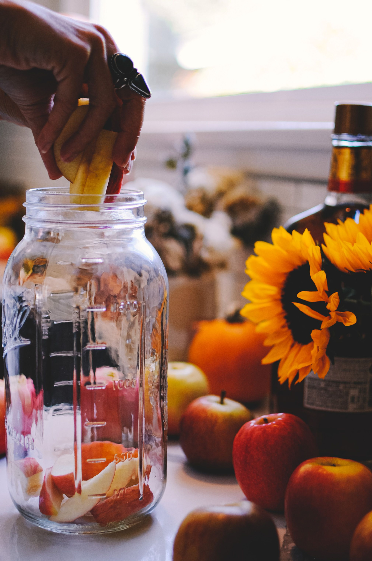 hand placing apple slices in a jar