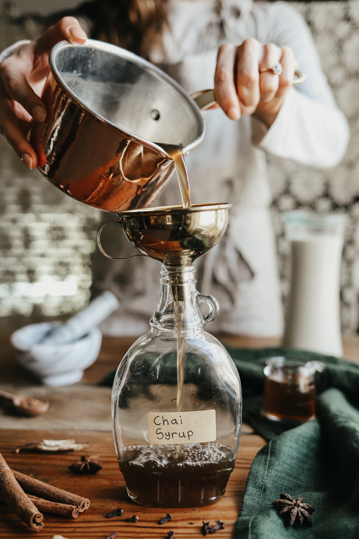 pouring chai syrup into a glass bottle