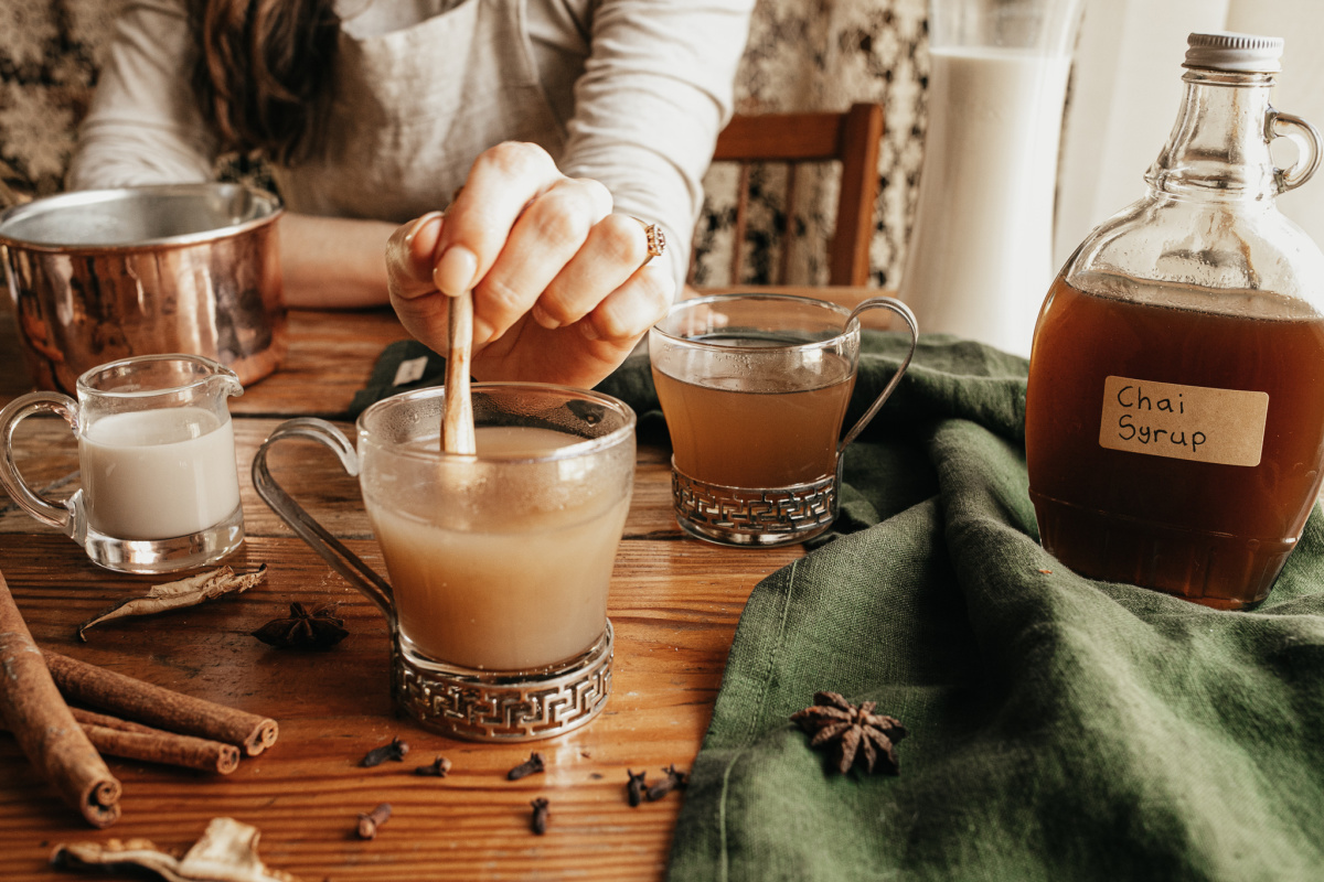 woman stirring chai syrup into a cup