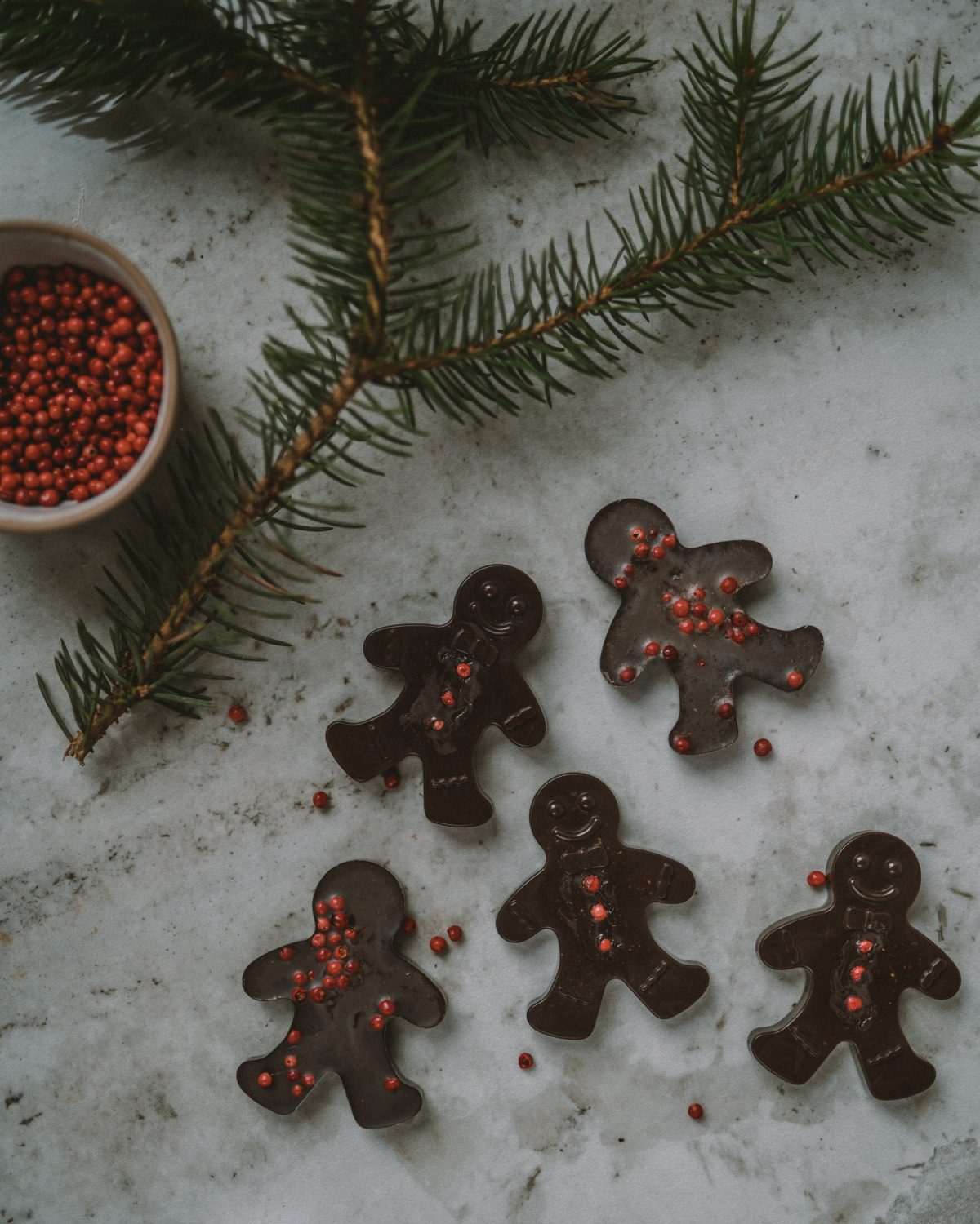chocolate gingerbread melts on a table with pine needles and peppercorns
