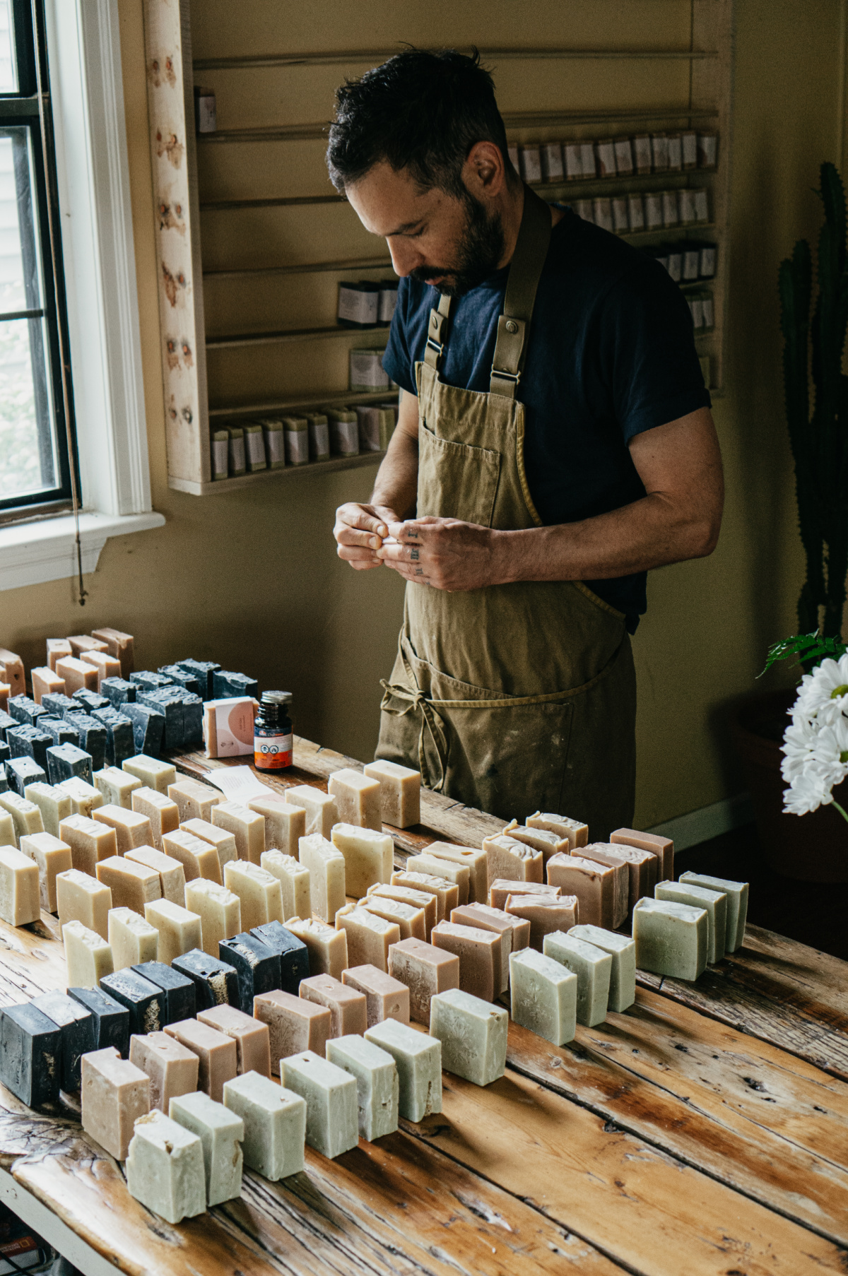 man standing at a table of handmade soap