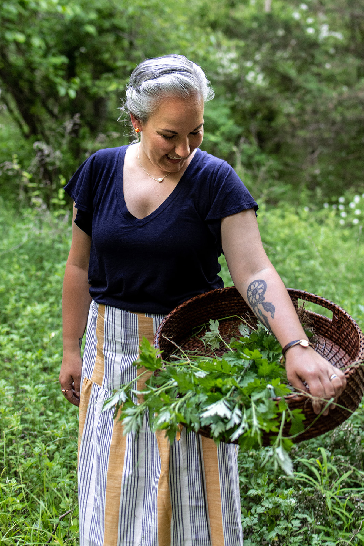 herbalist looking down at basket of foraged herbs