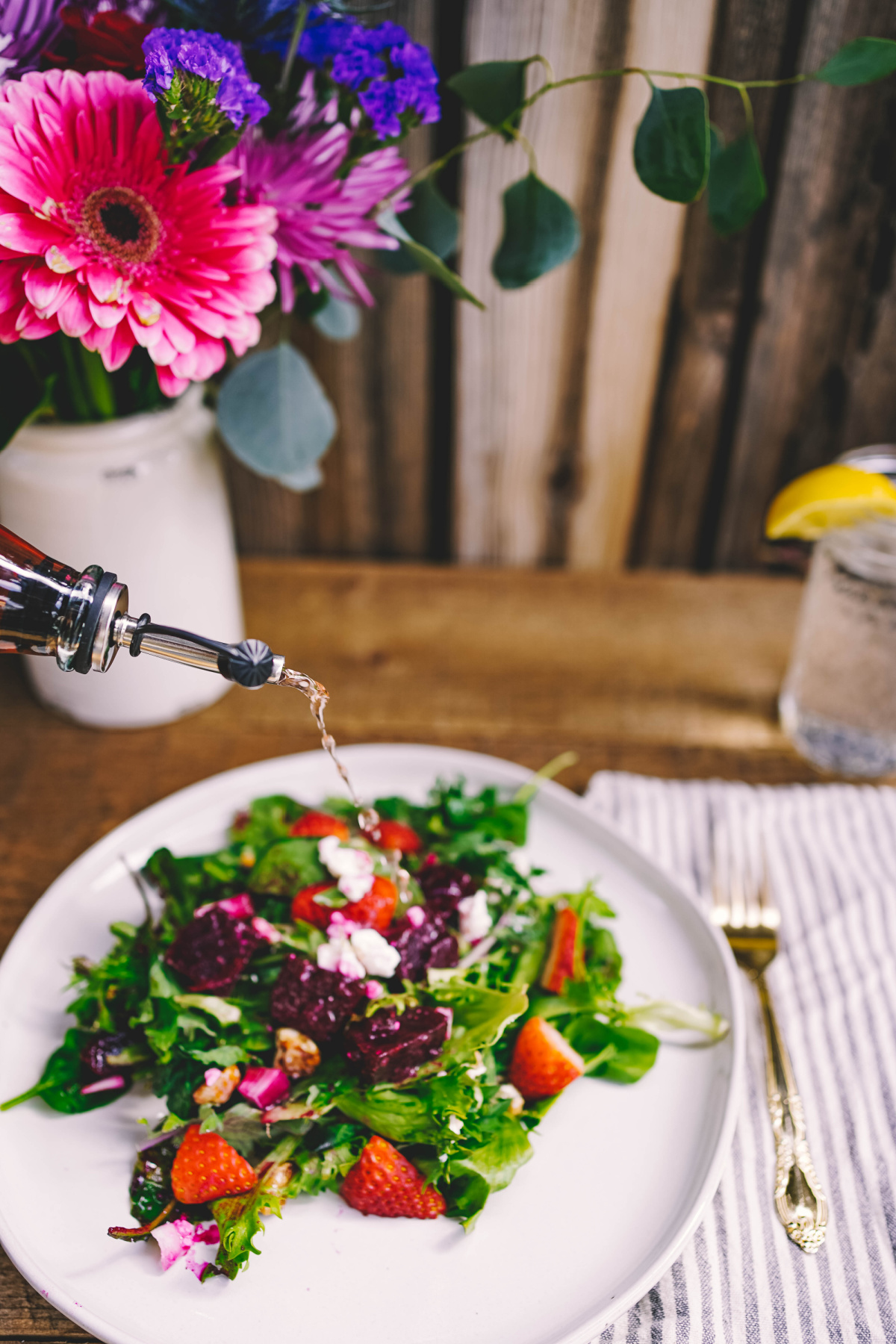 drizzling a floral vinegar onto a plate of salad