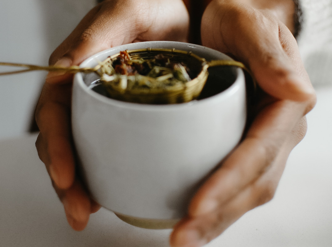 hands holding a mug of strained herbs