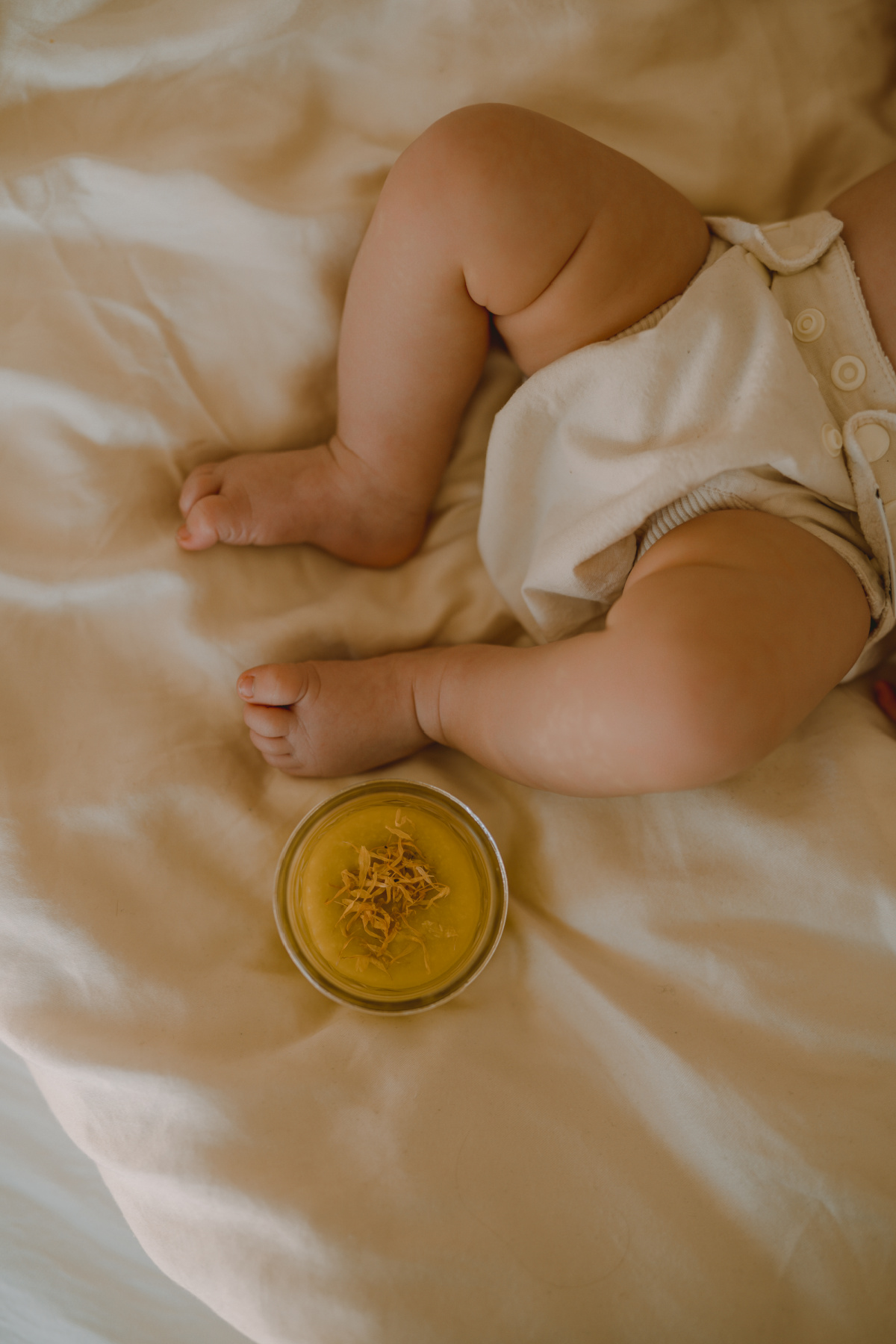 baby in a diaper with diaper balm on a blanket