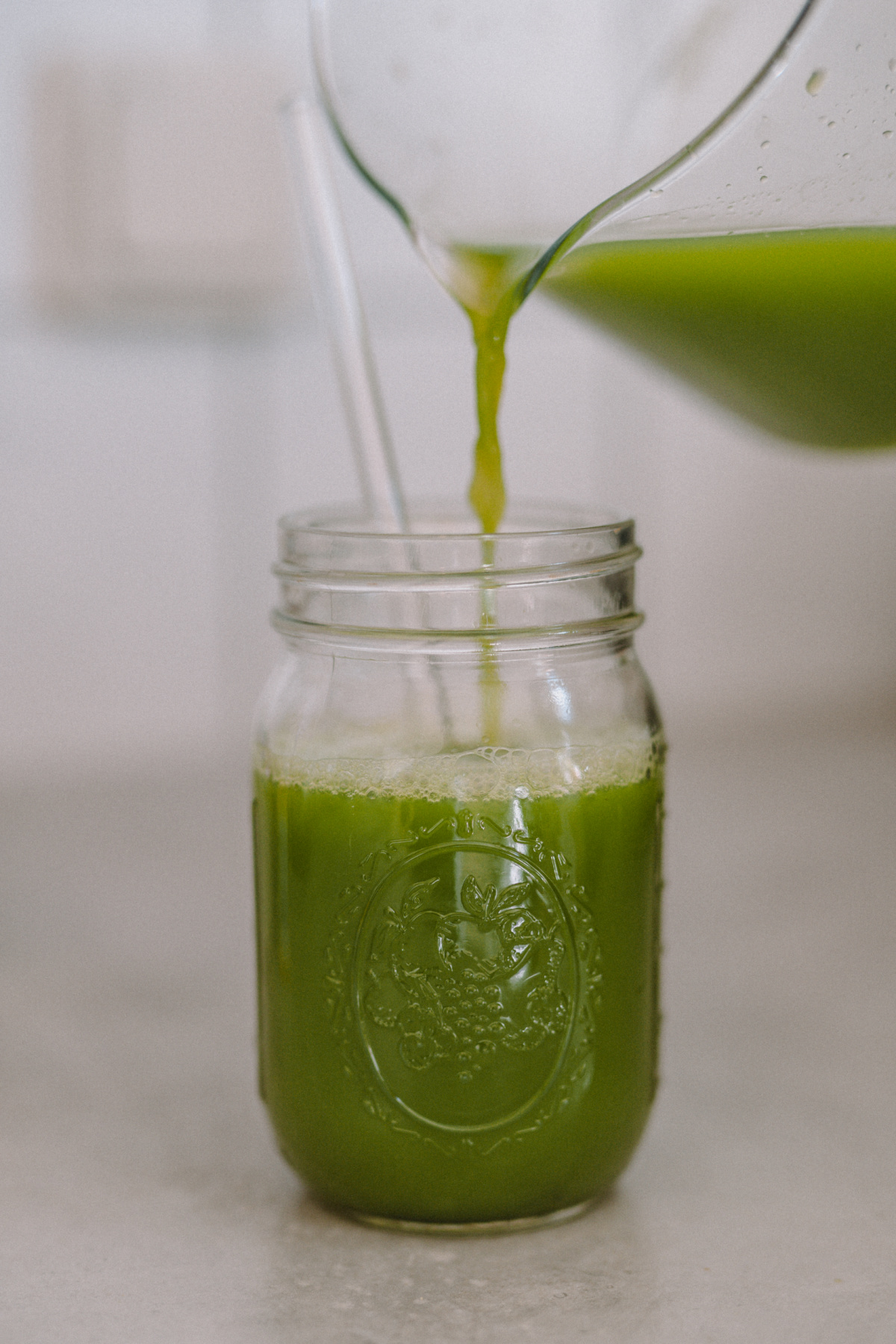 pouring green juice into mason jar