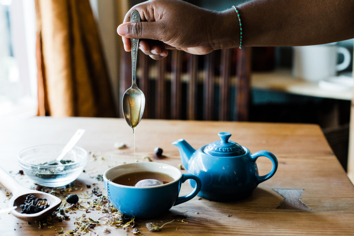 honey dripping off a spoon into a cup of tea