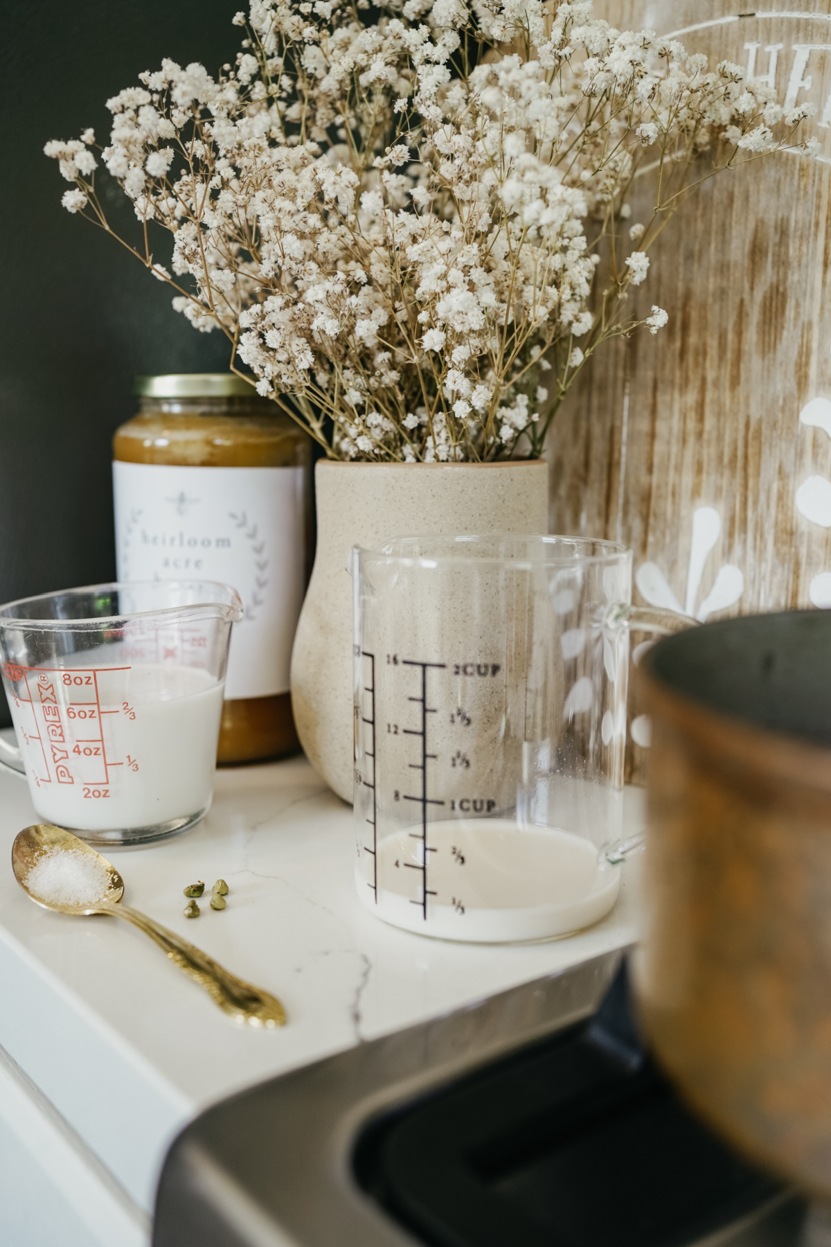 measuring cups and spoon with flowers and honey in background
