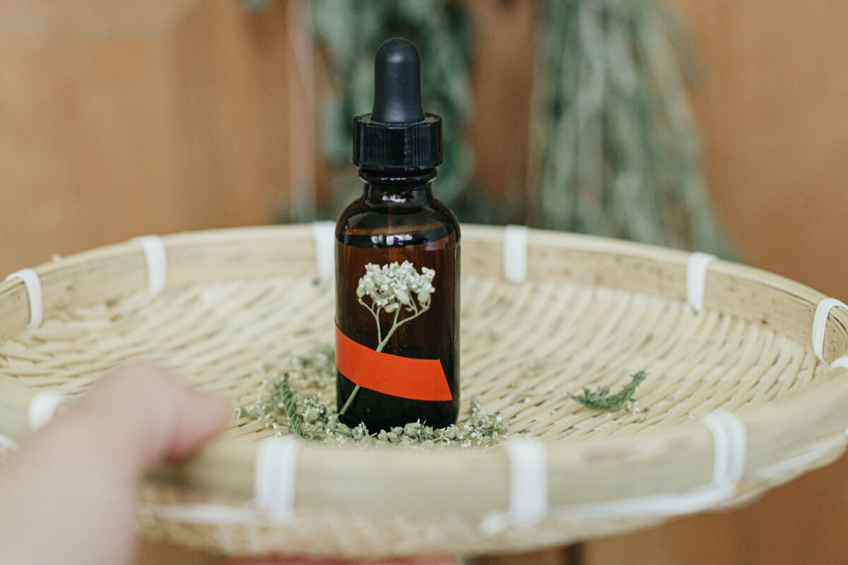 hand holding basket with yarrow tincture