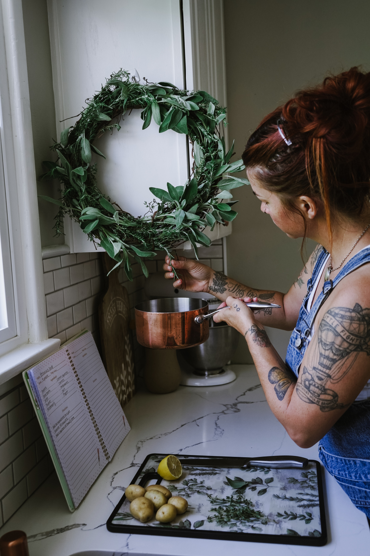 woman pulling herbs from wreath for cooking