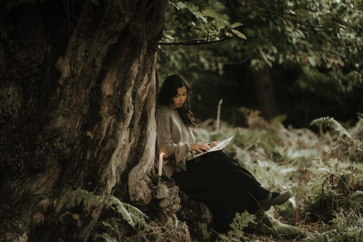 woman sitting on a tree reading by candlelight