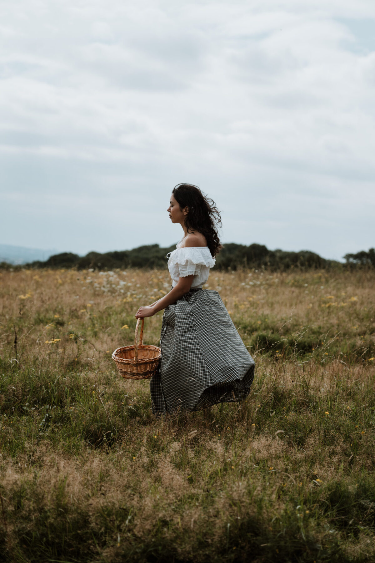 woman walking through field with basket