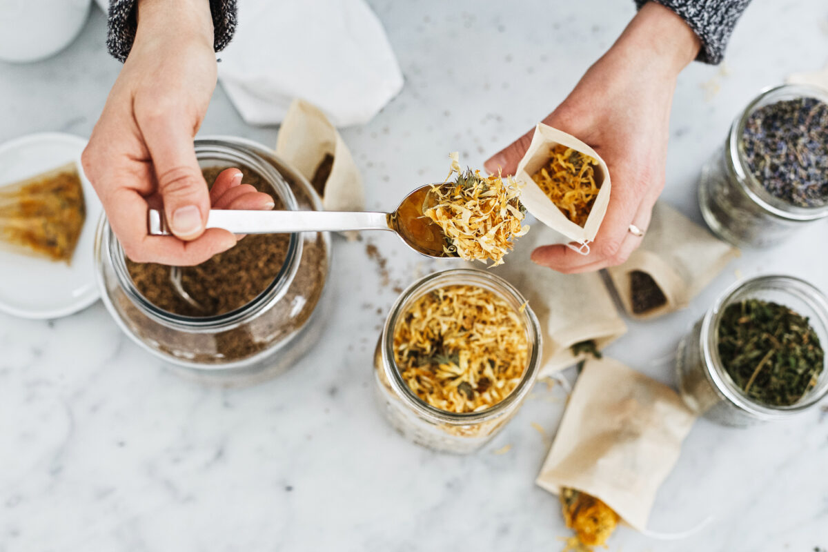 spooning herbs into a tea bag